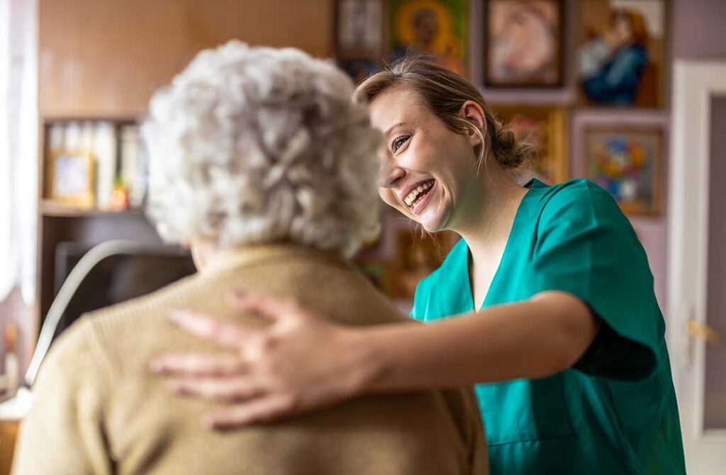 Family member and older adult talking quietly in a bright assisted living sitting room.