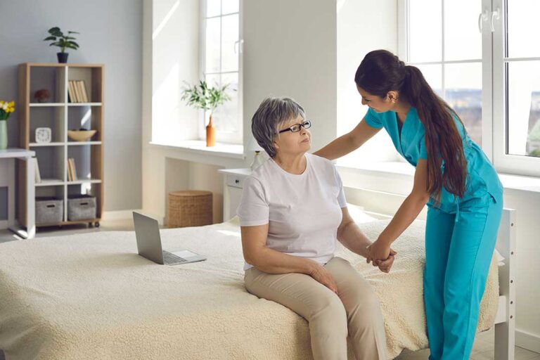 Staff member assisting an older adult during a fire drill in a residential hallway.